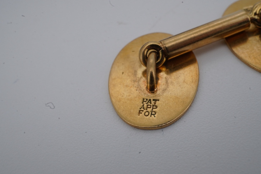 A pair of gold cuff-links, each end of oval outline with striped engraving, to a bar connector, each end 1.8cm, each stamped 18ct, combined gross weight approximately 9.5 grams, maker's marks EH, case stamped Jay's, Cond